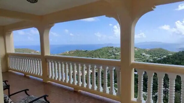 Ein Balkon mit weißer Brüstung mit Blick auf eine gebirgige Landschaft.