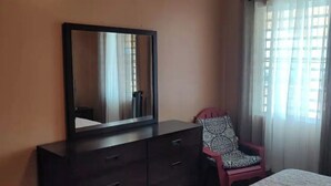 Ein Schlafzimmer mit Kommode, Stuhl und Bett.