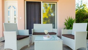 Eine Terrasse mit drei Korbstühlen und einem Glastisch, mit einem dekorativen Herz-Ornament.