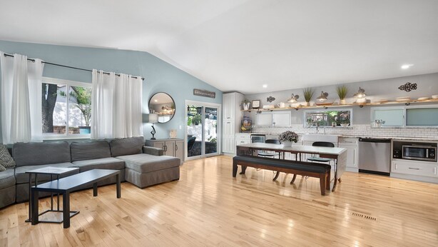 A modern living room with a sectional sofa, a coffee table, and a dining area with a bench.
