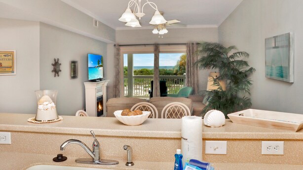 A modern kitchen with a large island, a built-in oven, and a view of the outdoors. - Dunes Club 1D (Port St. Joe)