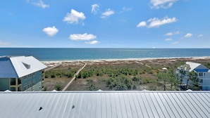 A coastal view with a beach, a building with a blue roof, and a clear sky. - Dunes Club 1D (Port St. Joe)