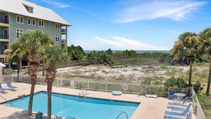 A pool area with lounge chairs, a pool, and a view of the beach. - Dunes Club 1D (Port St. Joe)