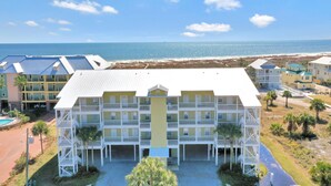 A multi-story hotel with balconies, a swimming pool, and a view of the beach and ocean. - Dunes Club 1D (Port St. Joe)