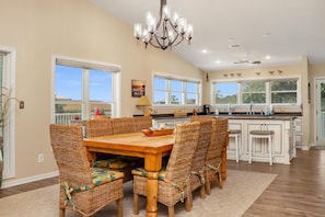 A spacious kitchen with a large island, ample natural light from windows, and a chandelier.