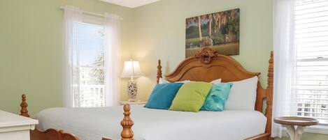 Un dormitorio con cama de madera, paredes verdes y un cuadro sobre la cama.