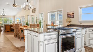 A spacious kitchen with a large island, white cabinetry, and a gas stove. - Sweet Home Apalachee (Port St. Joe)
