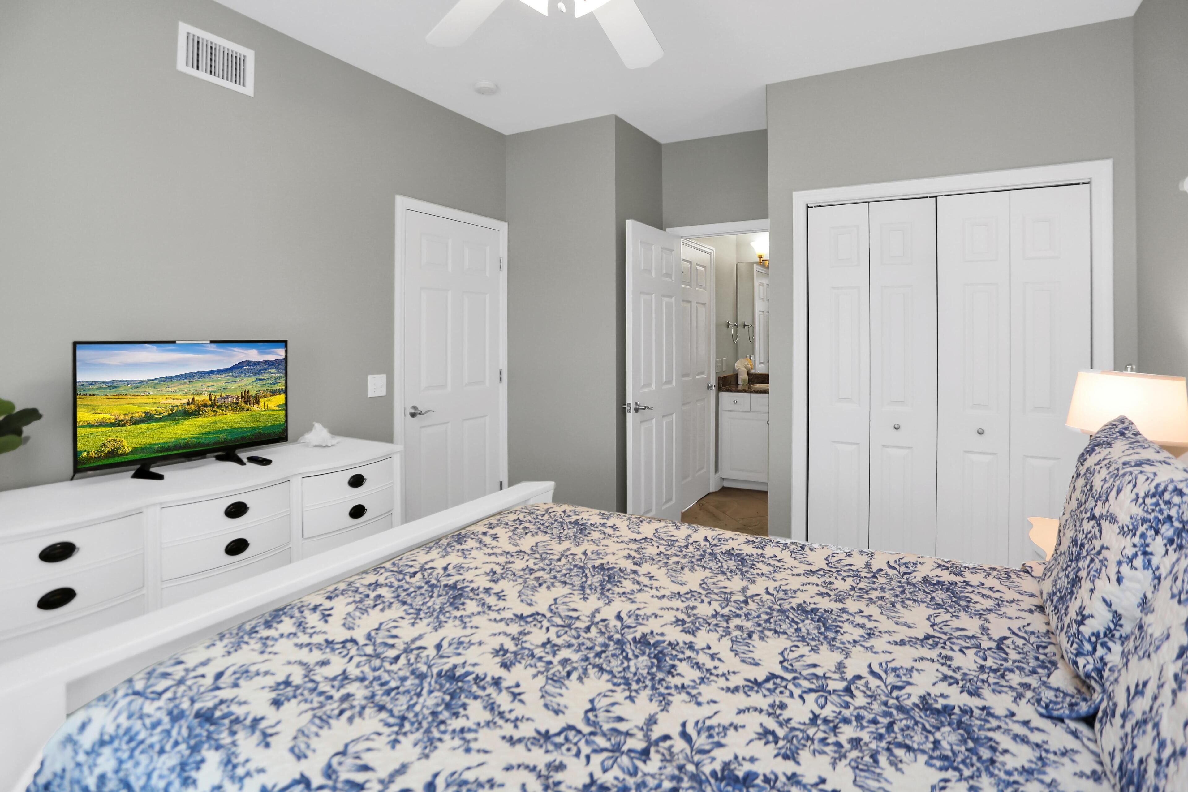 A bedroom with a bed, a television, a dresser, and a closet.