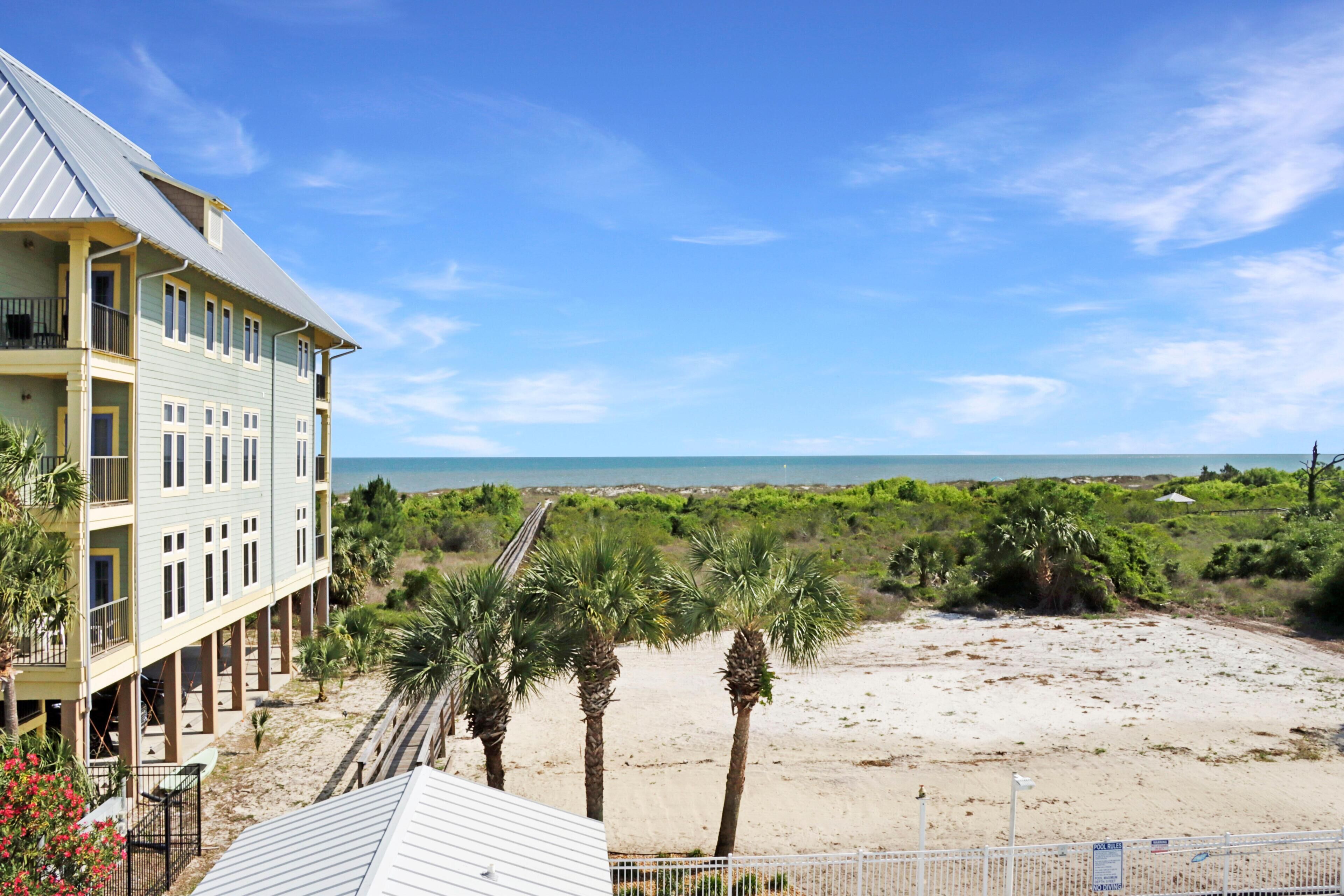 A beachfront hotel with a balcony, palm trees, and a view of the ocean.