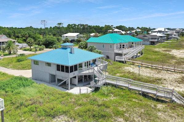 A coastal building with a blue roof, a balcony, and a staircase leading to a deck.
