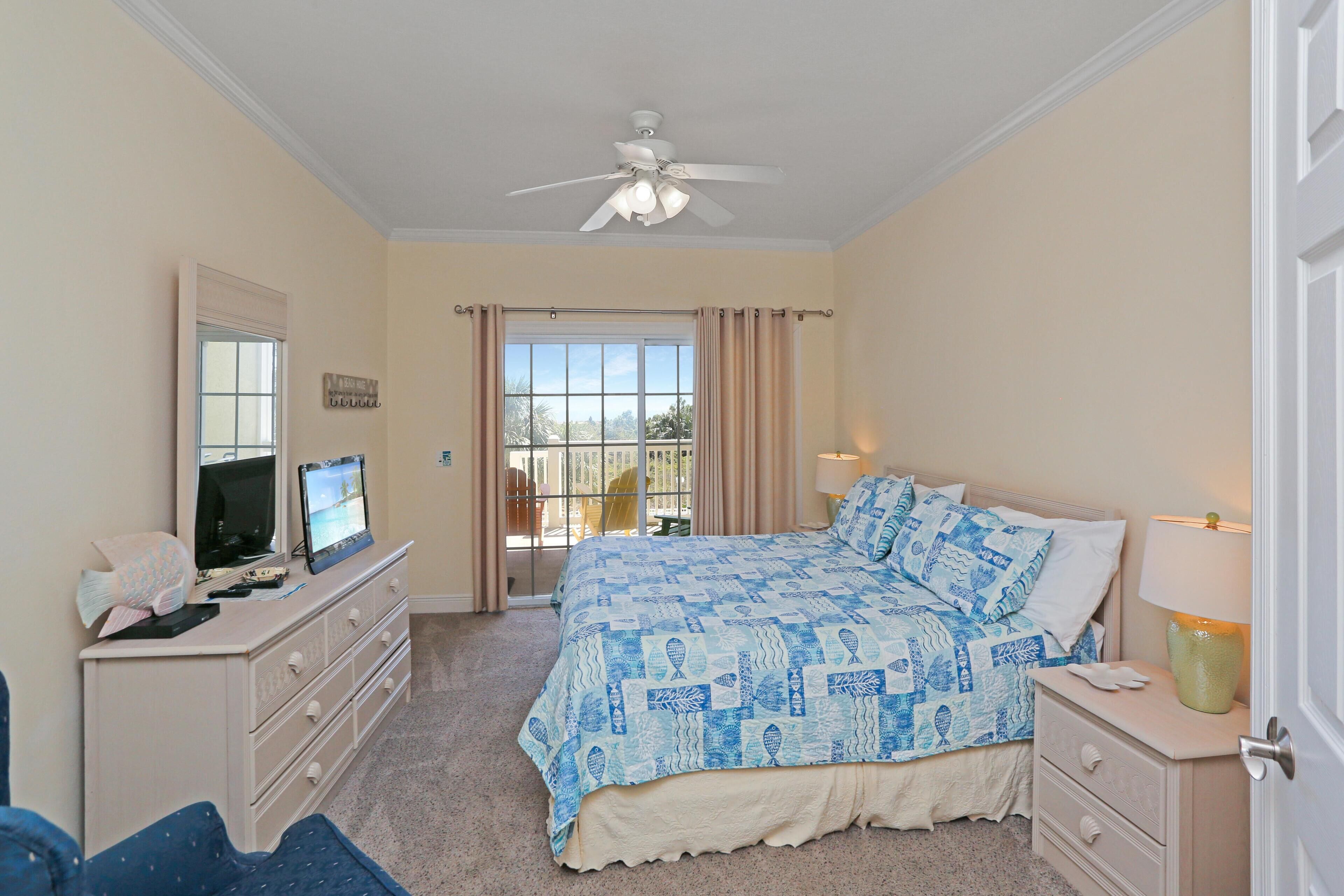 A bedroom with a bed, a dresser, a television, and a window with curtains.