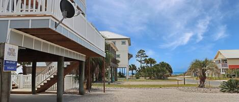 A beachfront property with a covered outdoor area, a staircase, and a sign for 'Pristine Properties'.