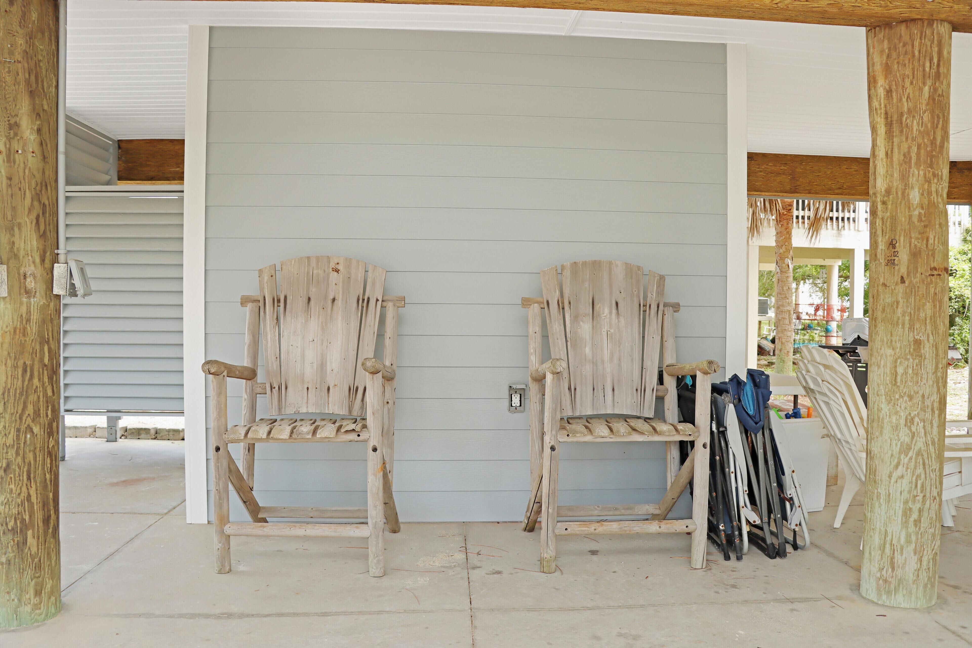 Two rustic wooden chairs with metal legs, a white door, and a wooden post.