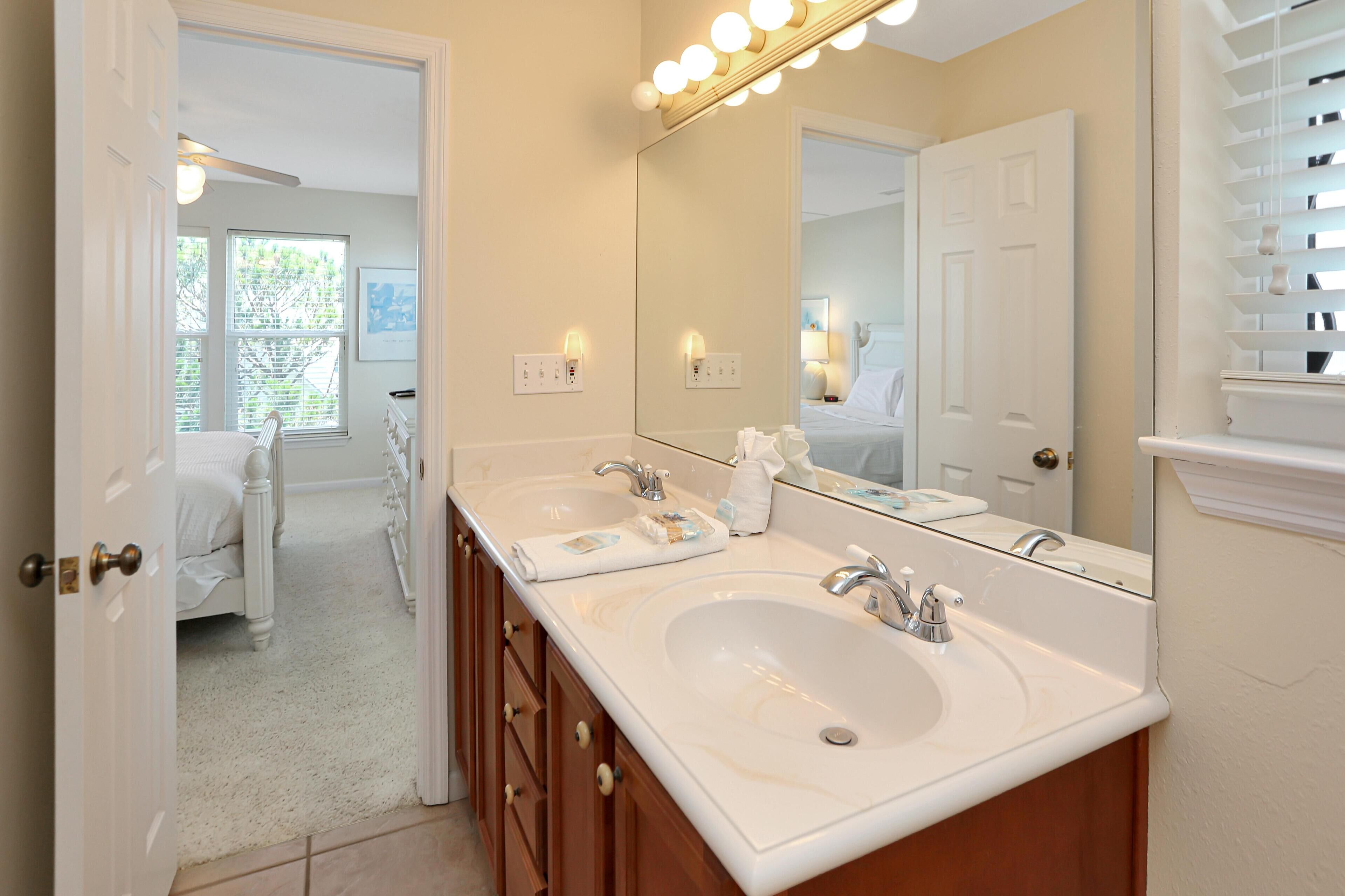 A bathroom with two sinks, a large mirror, and a ceiling fan.