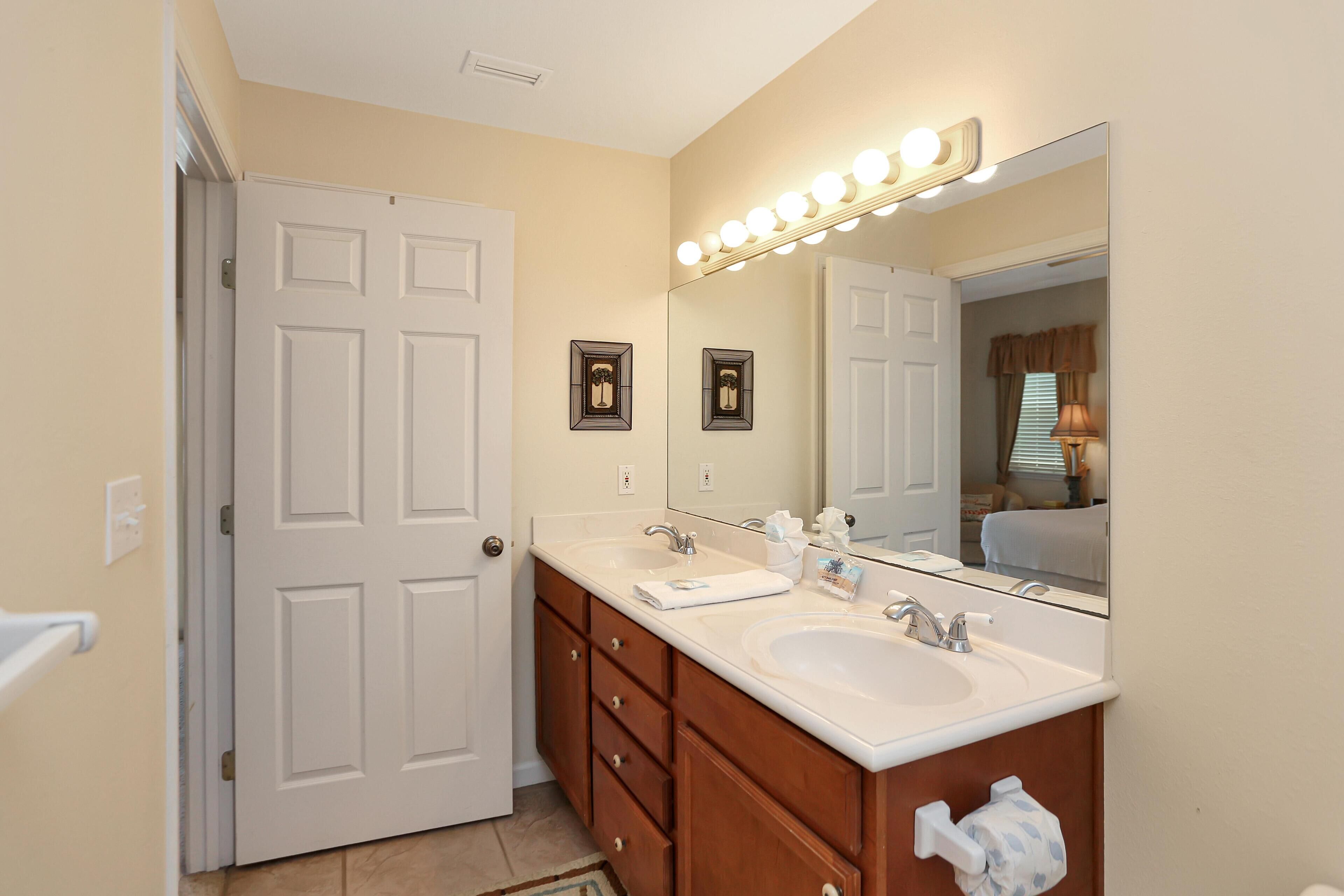 A bathroom with two sinks, a vanity, and a large mirror with lights.