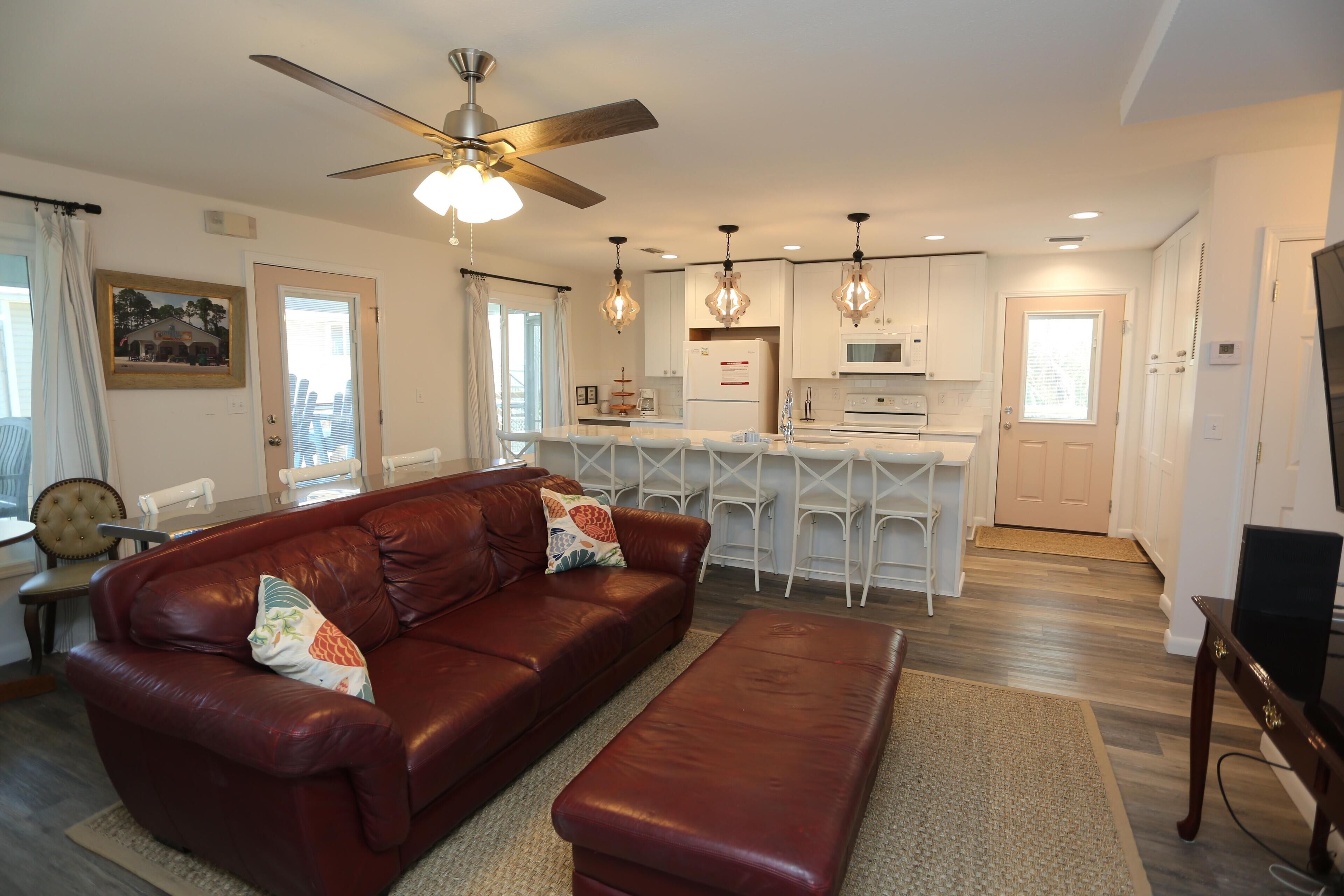 A modern living room with a leather sofa, a wooden bench, and a ceiling fan.