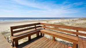 A wooden bench on a wooden deck overlooking a beach with the ocean in the background. - Pelican Landing 3 (Port St. Joe)