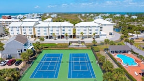 Um hotel com vários andares, quadra de tênis e área de piscina.