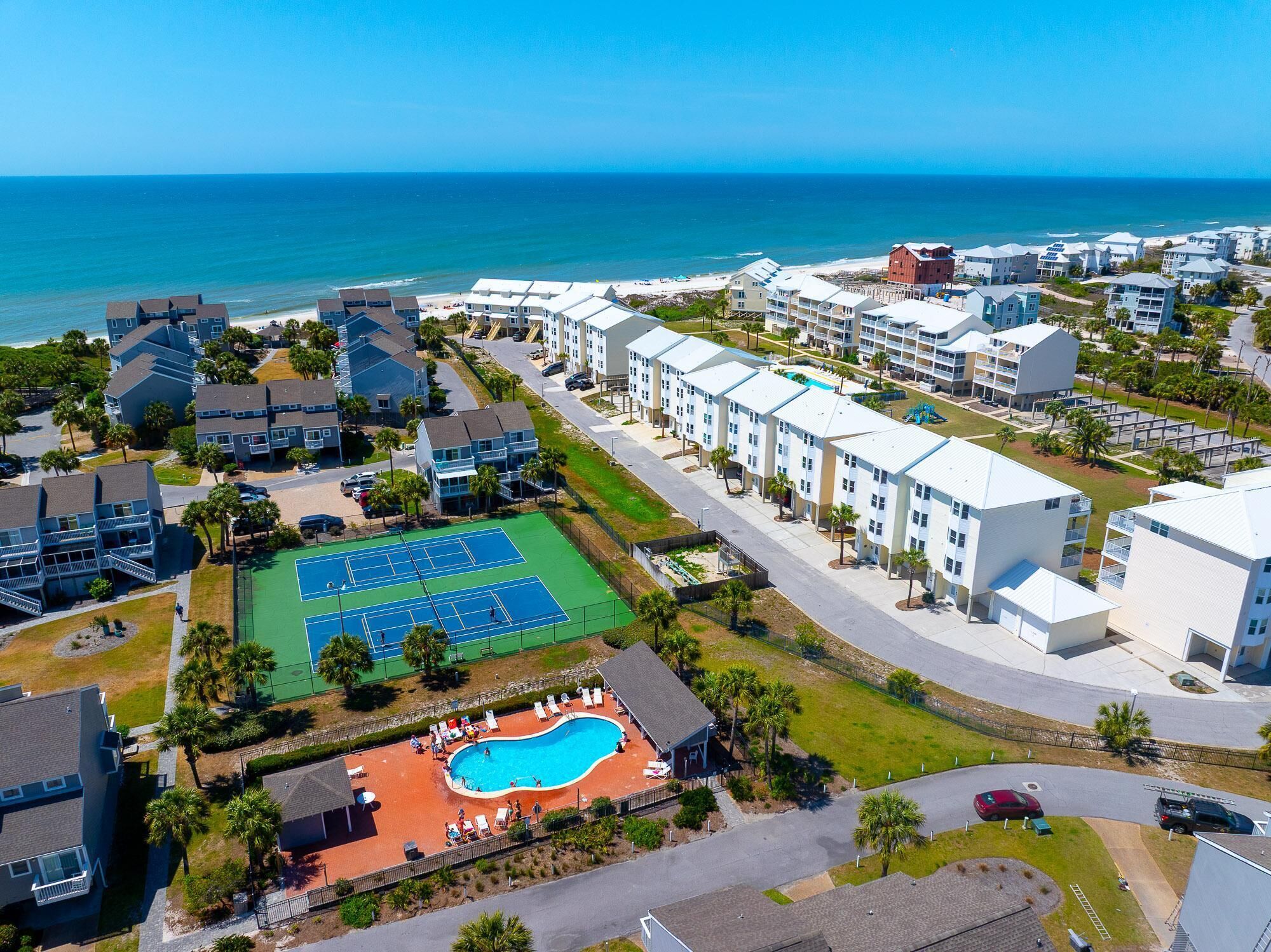 A coastal residential area with a tennis court, swimming pool, and beachfront views.