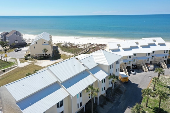 Un hotel costero con varias edificaciones, vista a la playa y zona de estacionamiento.