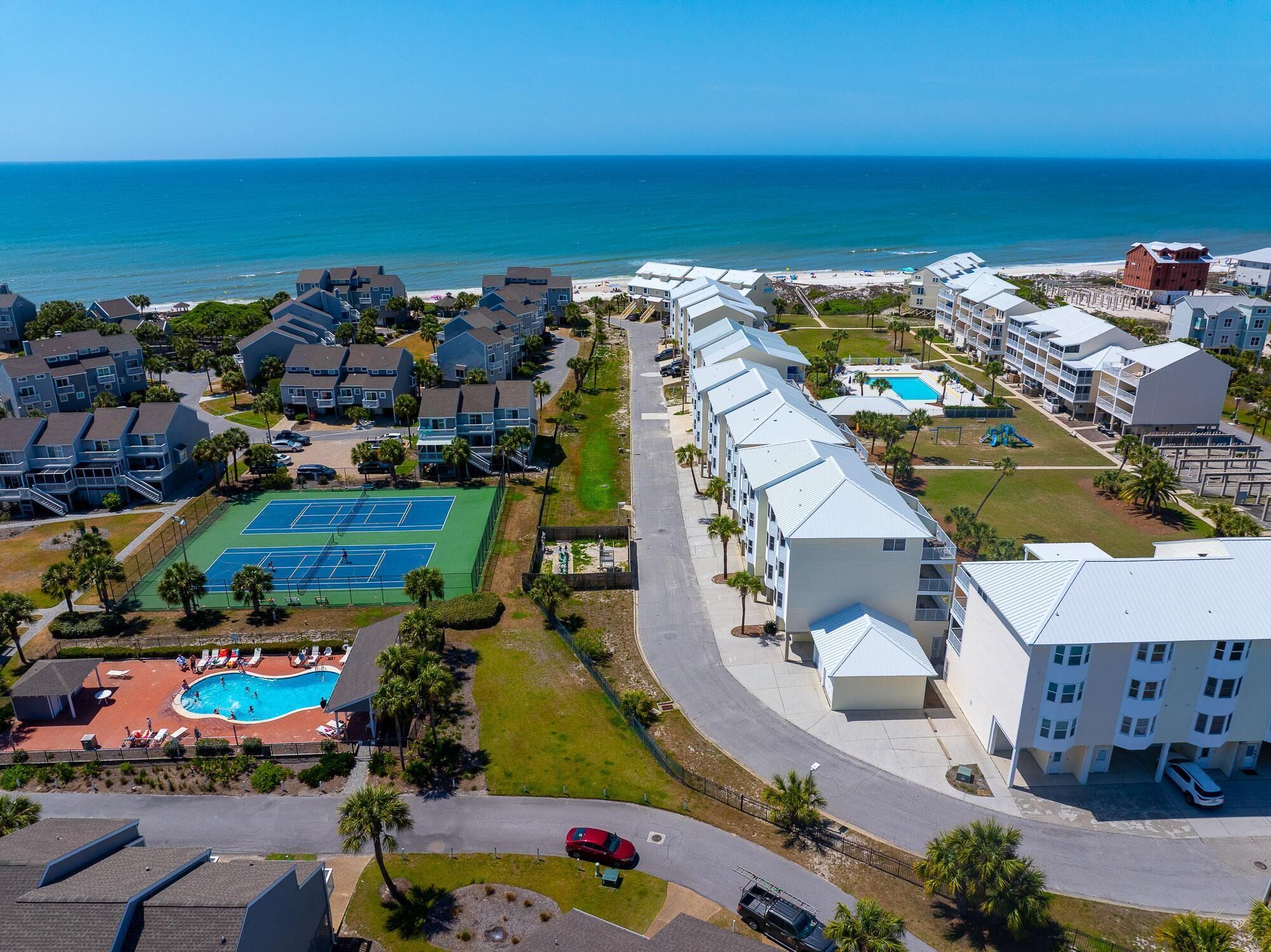 A coastal hotel with a tennis court, pool, and ocean view.