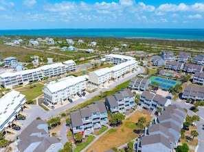 A coastal residential area with multiple apartment buildings, a tennis court, and a view of the ocean. - Sea Cliff B-2 (Port St. Joe)