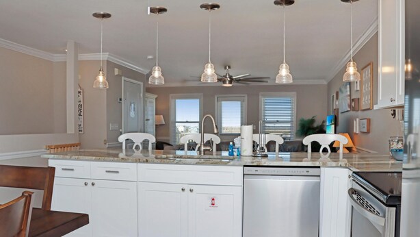 Una cocina moderna con iluminación colgante, ventilador de techo y lavavajillas.