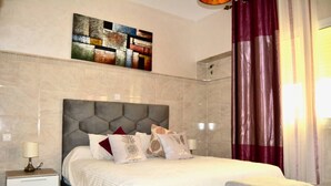 Ein Hotelzimmer mit Marmorwand, einem großen Bett mit vielen Kissen, einem Nachttisch mit Lampe und einem Gemälde über dem Bett.