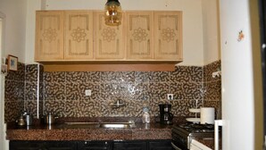 Eine Küche mit Granit-Arbeitsplatten, einem Spülbecken, einem Herd und dekorativen Holzschränken mit floralem Muster.
