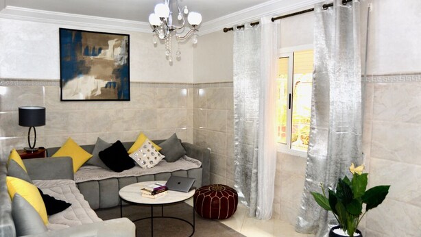 Ein modernes Wohnzimmer mit einem grauen Sofa, einem runden Couchtisch und einer Chandelier.