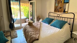 A bedroom with a bed, a window with curtains, a ceiling light, and a painting on the wall. - 5 minutes from the beach, quiet renovated house with wifi, air conditioning and jaccuzi (CANET EN ROUSSILLON)