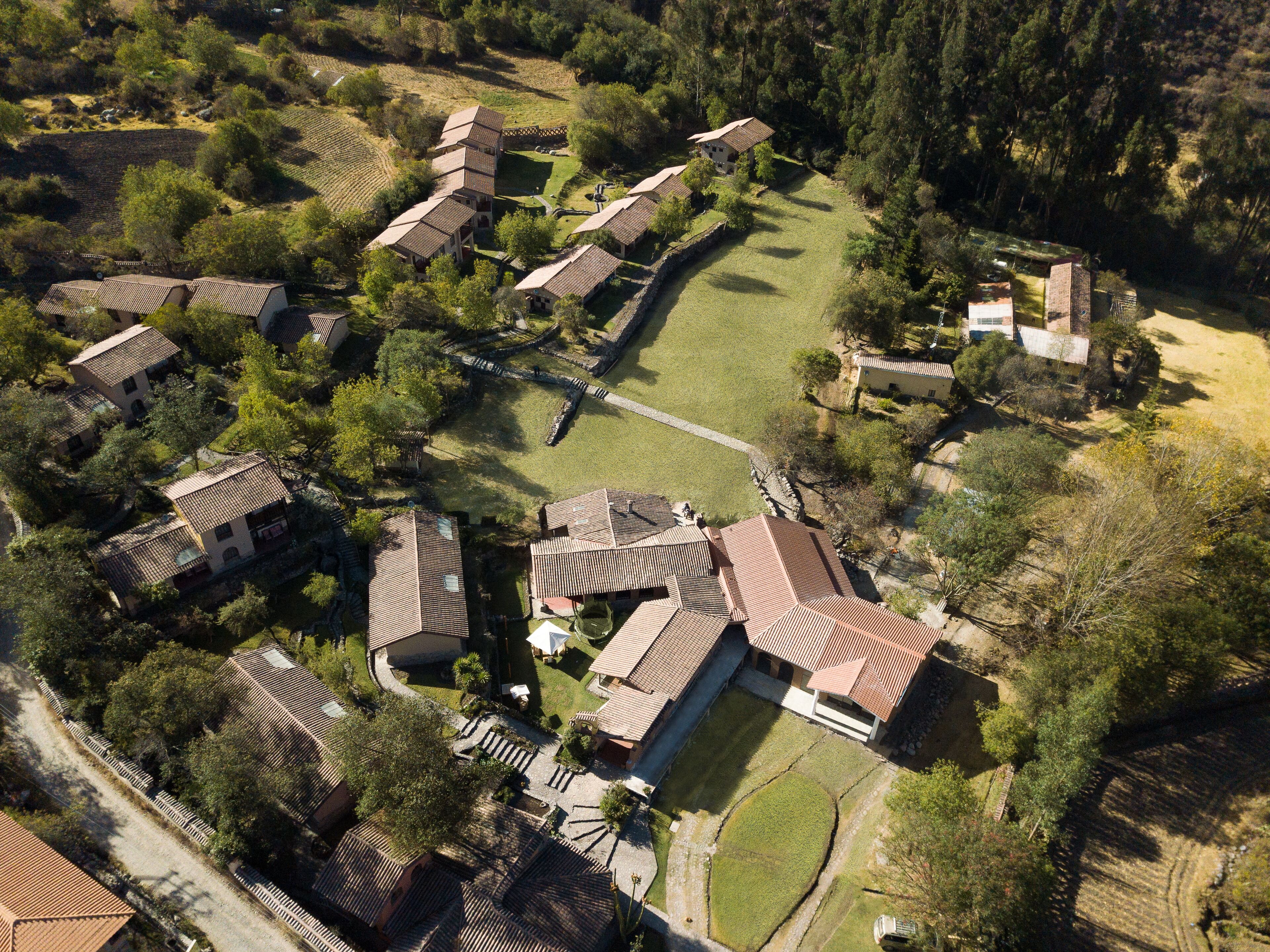 An aerial view of a residential area with multiple houses, a central pathway, and surrounding greenery.