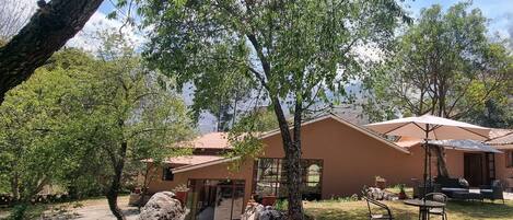 A house with a tiled roof, a patio with a table and chairs, and a view of the surrounding trees and landscape.