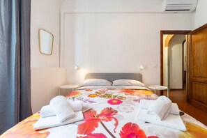 Une chambre d’hôtel avec un lit, deux tables de chevet, un miroir et une armoire en bois.