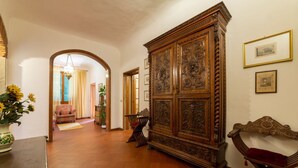 Un couloir avec une grande armoire en bois, un banc et une porte donnant sur une autre pièce.