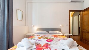 Une chambre d’hôtel avec un lit, deux tables de chevet, un miroir et une armoire en bois.
