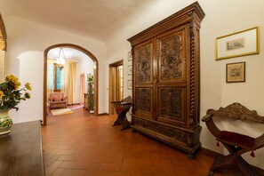 Un couloir avec une grande armoire en bois, un banc et une porte donnant sur une autre pièce.