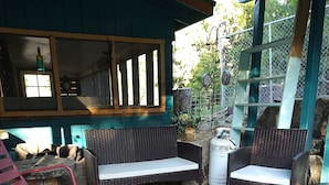 A covered outdoor seating area with wicker furniture, a fire pit, and a metal grill. - Cabin 8 miles from Kings Canyon entrance gate. (Miramonte)