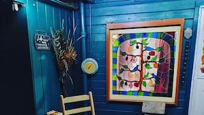 A wooden chair in front of a blue wall with a stained glass window depicting fruit and birds. - Cabin 8 miles from Kings Canyon entrance gate. (Miramonte)
