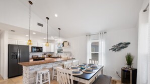 A modern kitchen with white cabinetry, a granite countertop, and a dining area with a table set for four.