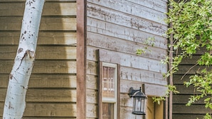 A wooden house with a window and a door, surrounded by greenery. - Teton National Park Avails! Great Location, Games, Laundry, & Playround! (Driggs)