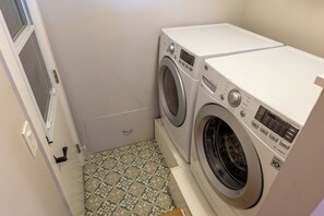 Une buanderie équipée de deux machines à laver, d’une porte et de carreaux de sol à motifs.