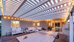 An outdoor patio with a ping pong table, seating area, and string lights.
