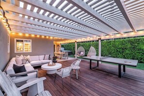 An outdoor patio with a wooden deck, white furniture, and string lights.