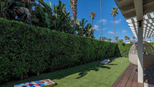 A well-maintained outdoor area with a wooden deck, a lawn, and a hedge. - Cozy Private Beach House - Steps from the beach (Oceanside)