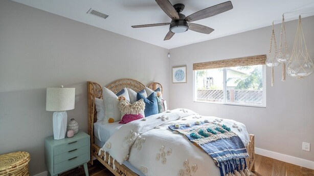 Une chambre à coucher comprenant un lit, une table de chevet, un ventilateur de plafond, une fenêtre avec vue et un luminaire suspendu.