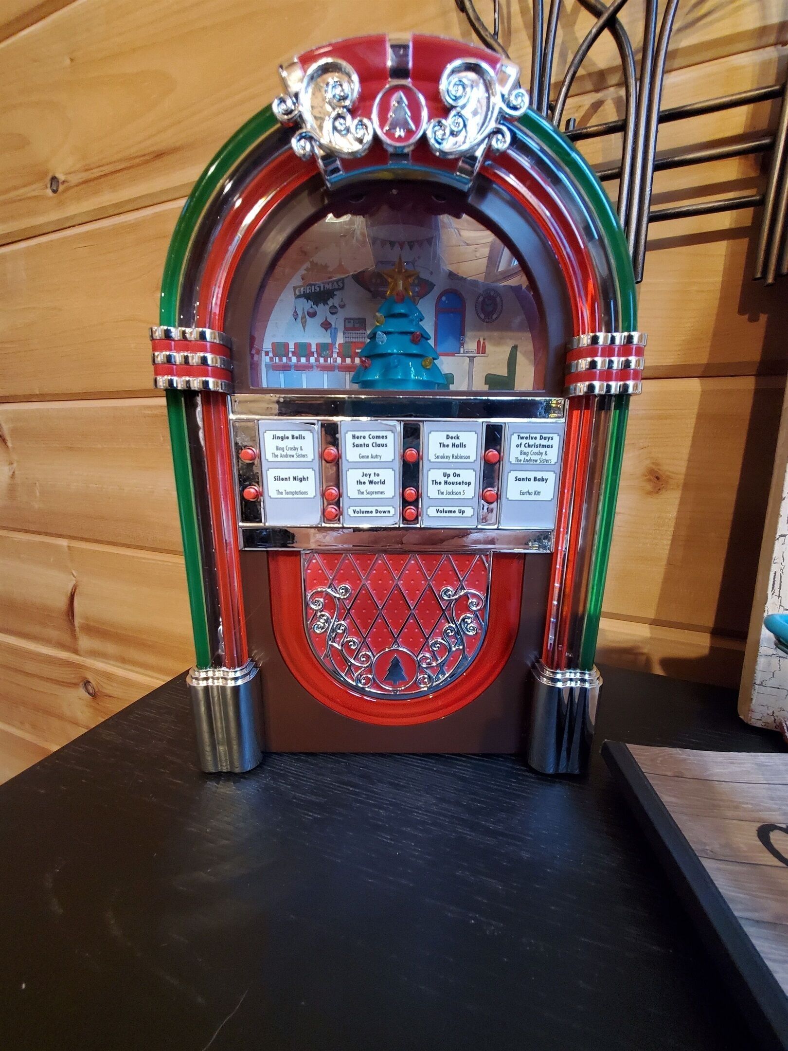 A jukebox with a Christmas theme, featuring a red and green color scheme and a decorative top.