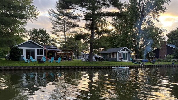A lakeside property with a dock, a small boat, and outdoor seating.