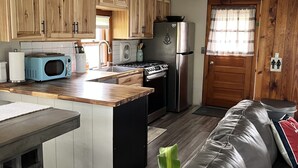 A compact kitchen with wooden cabinets, a microwave, a stove, and a refrigerator.