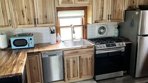 A kitchen with wooden cabinets, a microwave, a dishwasher, a stove, and a refrigerator.